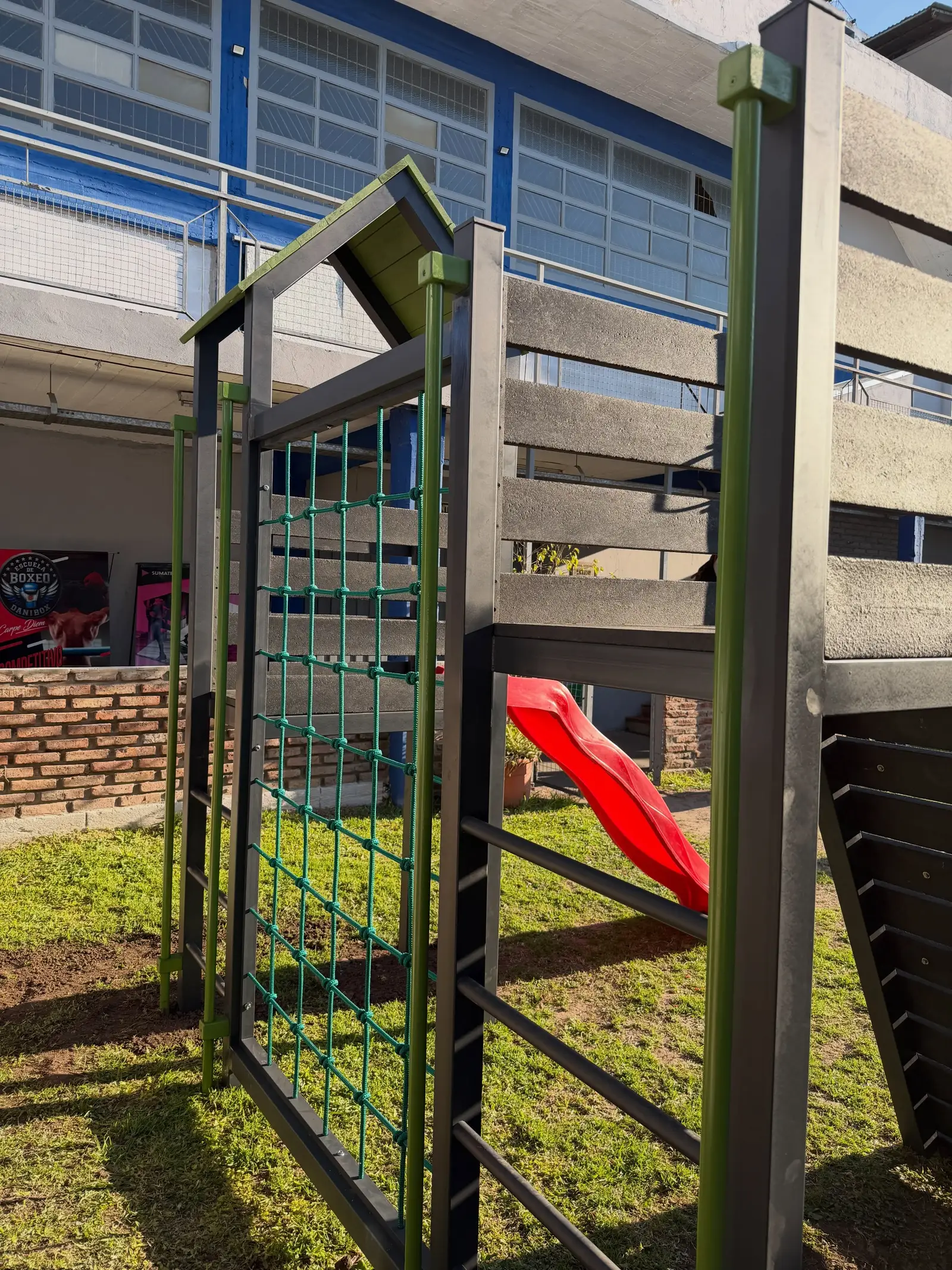 Vista posterior con red de trepa, escalera y plataforma de juego