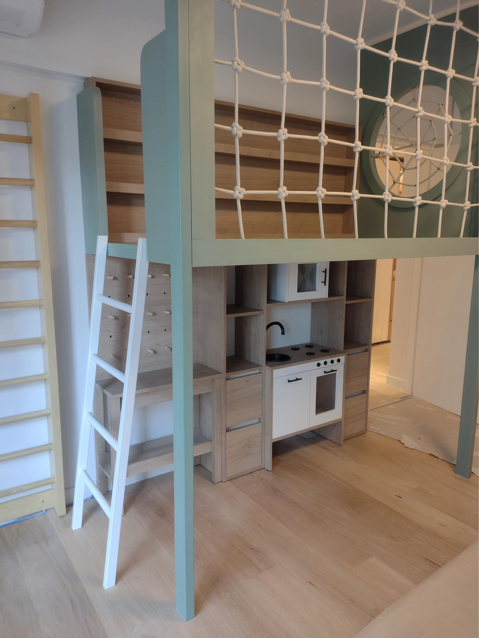 Cuarto de juego y descanso con estructura elevada, red y sector de cocina.