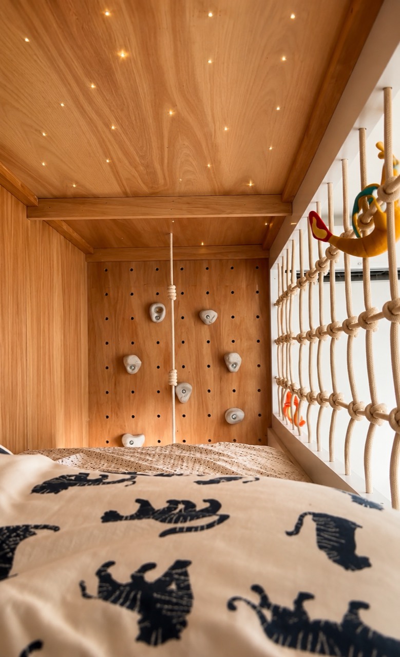 Cama elevada de Habitación Leonel con cielo estrellado, red y muro de escalada