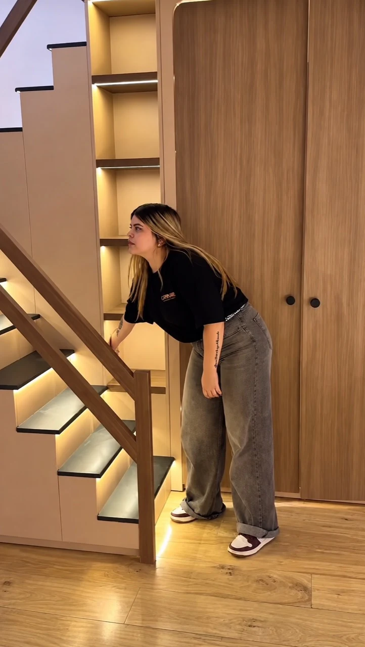 Dormitorio a medida con cama baja, mesa de luz, escalera iluminada y guardado integrado.
